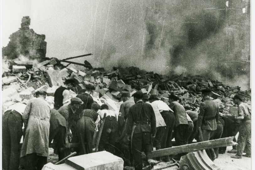 Menschen über den Trümmern der Hauptbahnhofs Stuttgart, Rauch hängt über dem Bahnhof